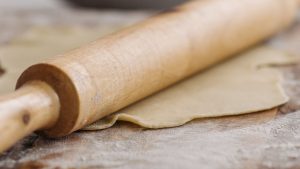 A Close-Up Shot of a Rolling Pin Over a Dough