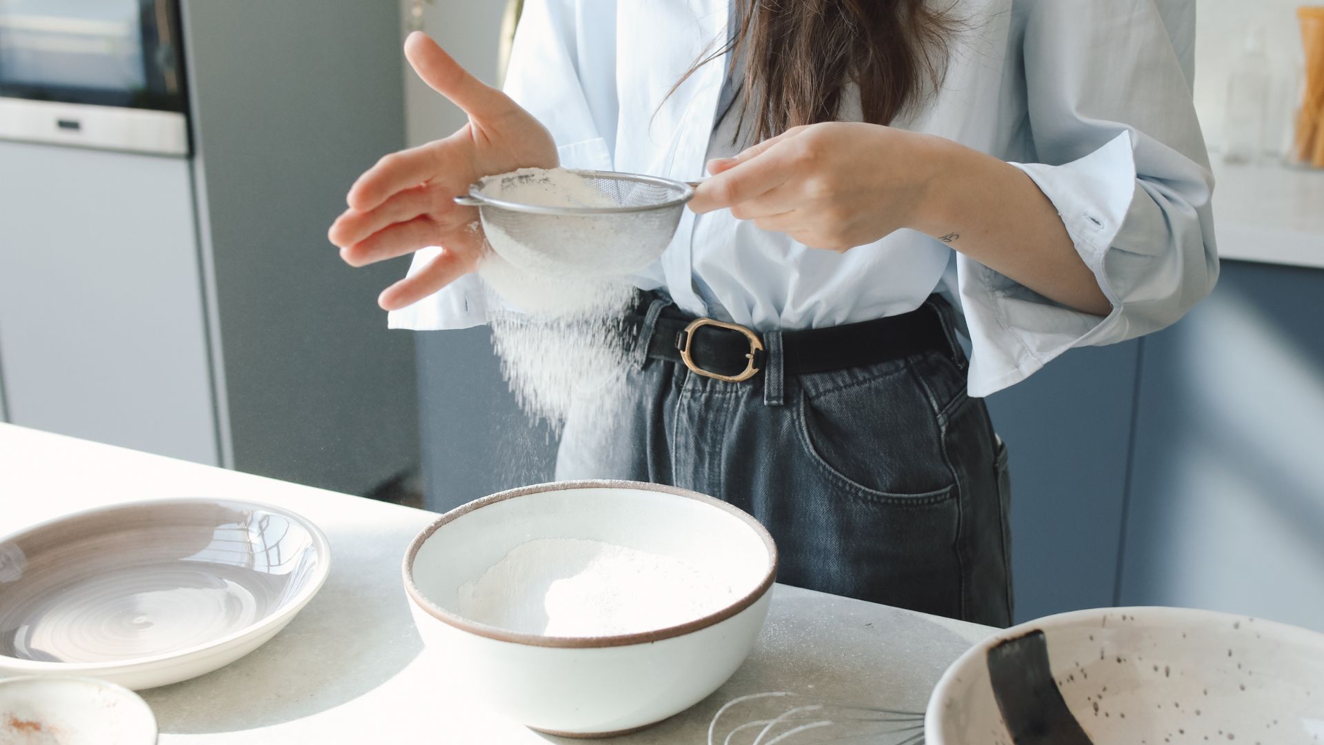 A Person Putting a Scoop of Flour on a Colander