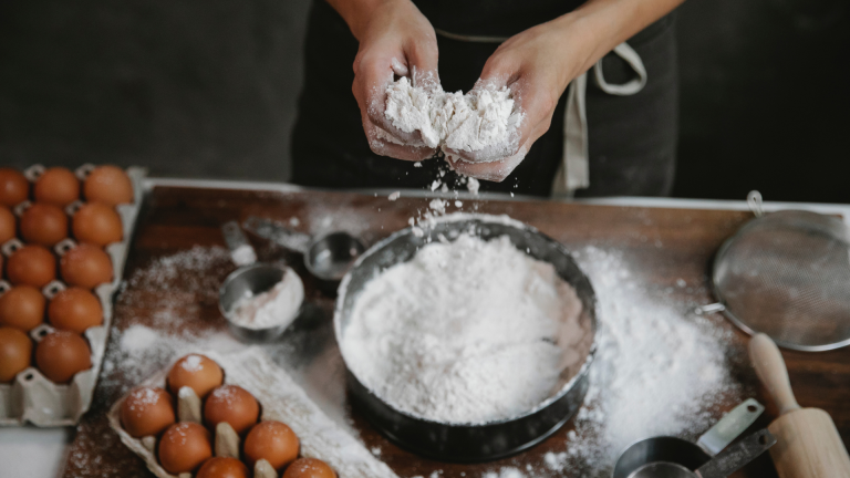 Cook adding flour to recipe of dough