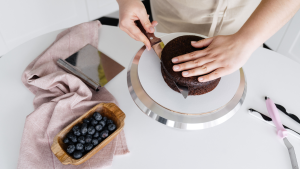 Crop cook cutting cake on table