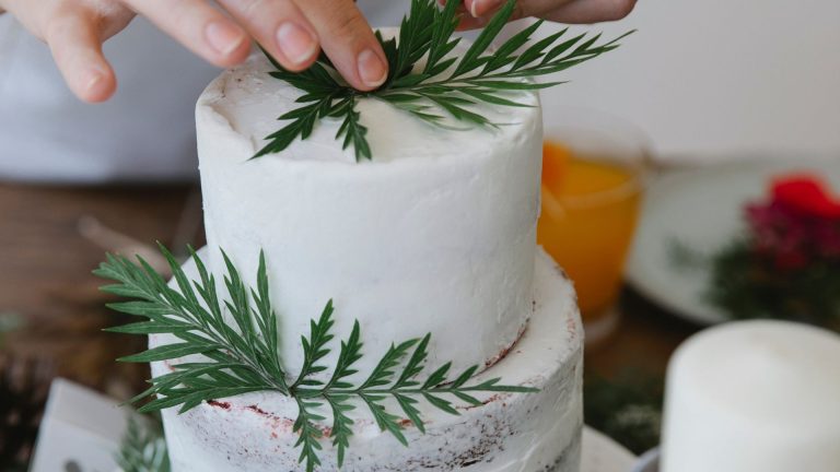 Crop woman decorating cake with herbs