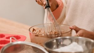 Crop woman mixing batter in kitchen