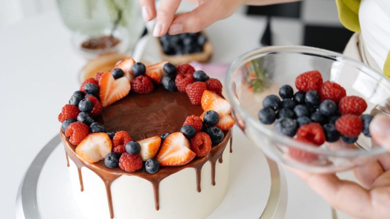 Female confectioner decorating homemade cake with berries