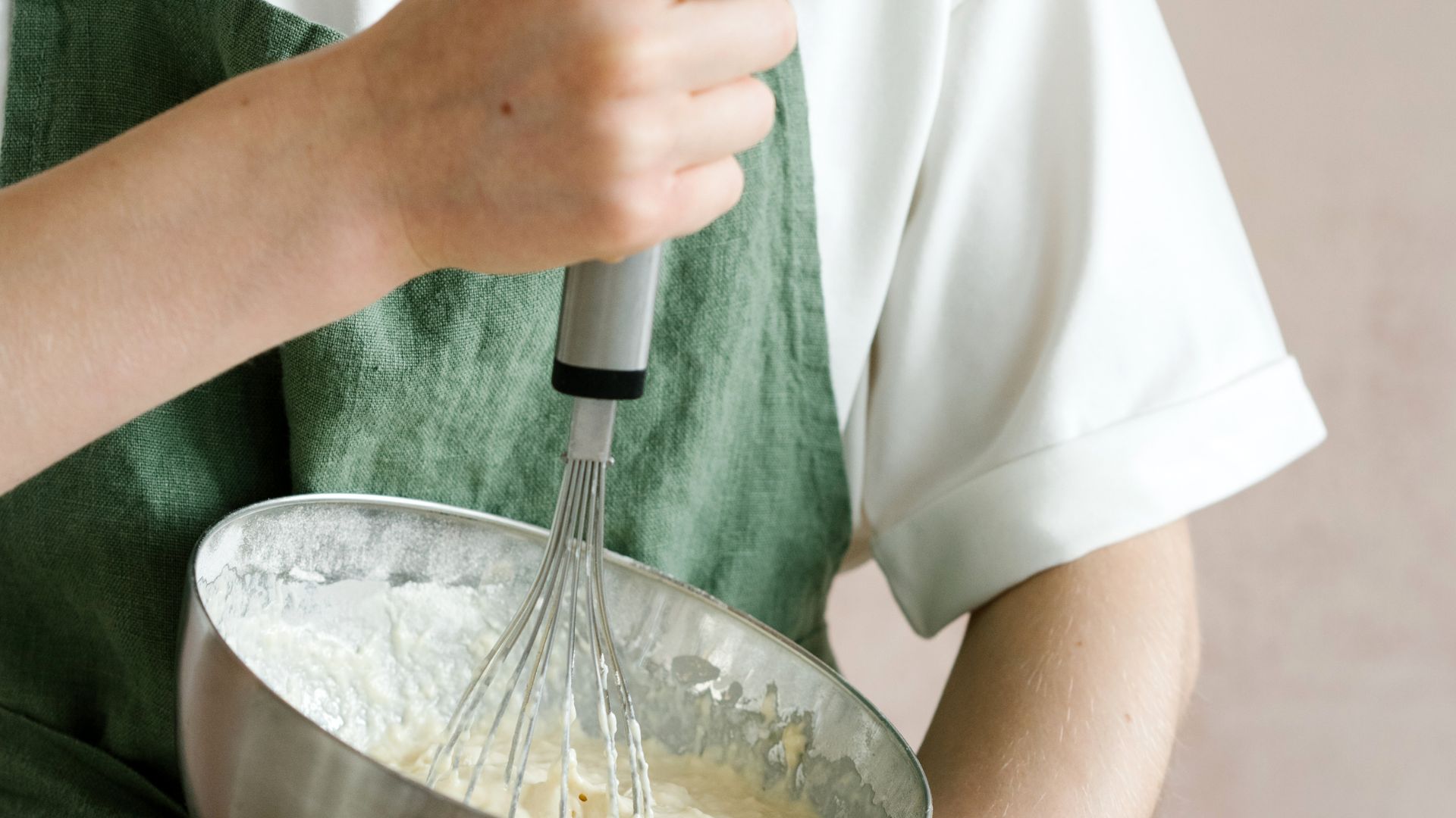 Female mixing ingredients in bowl with whisk