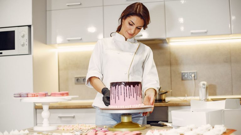 Focused confectioner garnishing cake in kitchen