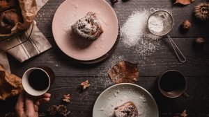 Person Holding Mug Beside Two Plates of Pastry