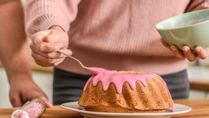 Person Putting Icing on a Cake