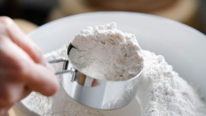Person Scooping Flour with a Measuring Cup