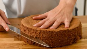 Person Slicing a Whole Cake in Half