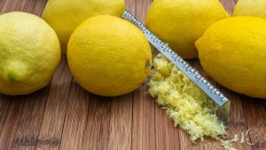 Ripe lemons with zest and grater on table