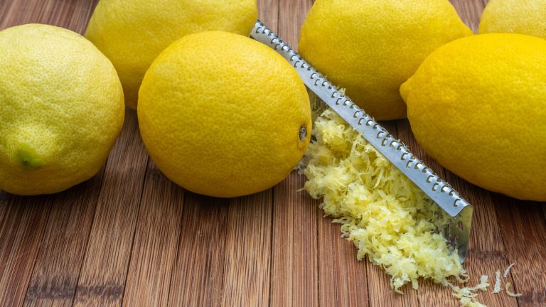 Ripe lemons with zest and grater on table