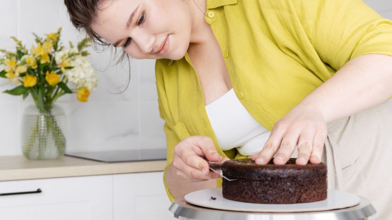 Woman cutting biscuit while preparing cake