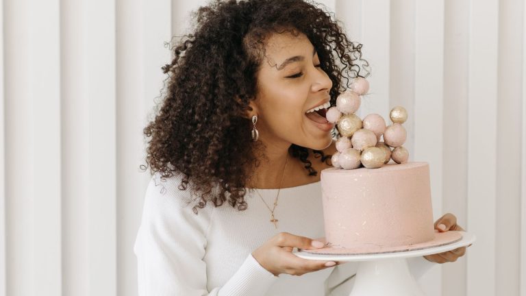 Woman with Curly Hair Eating a Pink Birthday Cake